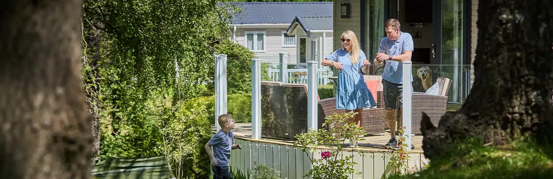 Couple on forest holiday caravan decking talking to boy