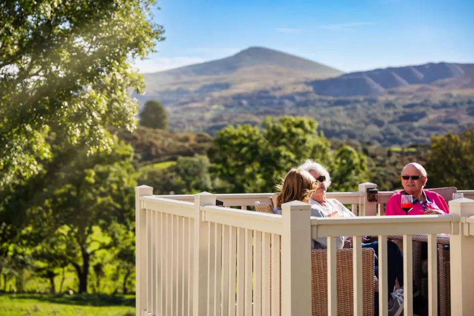 Family sitting on decking with view panoramic views overlooking Snowdonia National Park