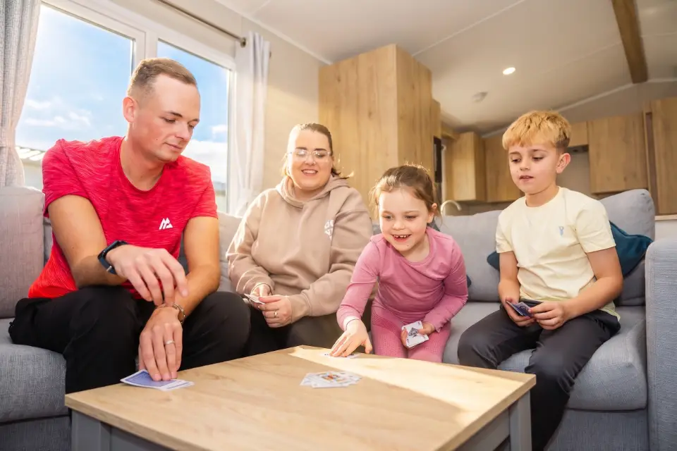 Family playing cards in their used caravans for sale