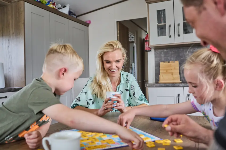 Family playing board games in their new static caravan purchased from Lyons Holiday Parks